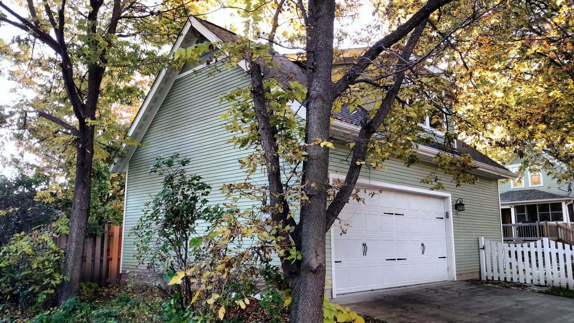 A house with white garage doors and a tree in front
